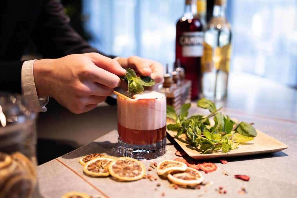 A cocktail being created with lemon and herbs at nox bar in voco™ Brussels City North