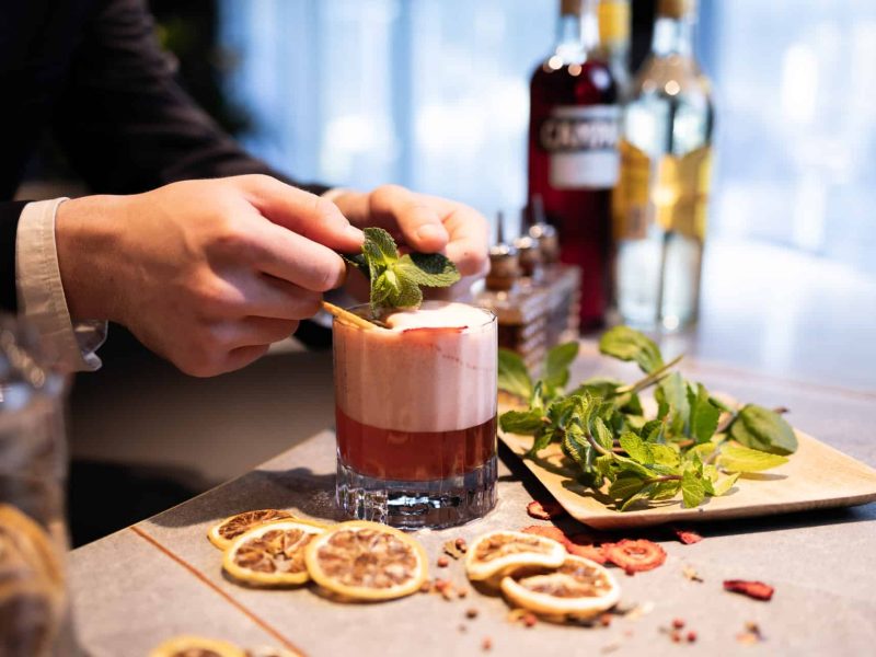 A cocktail being created with lemon and herbs at nox bar in voco™ Brussels City North
