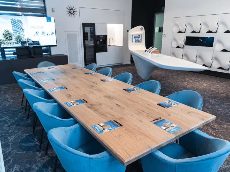 Meeting room with wooden table and voco building presentation on the tv screen.