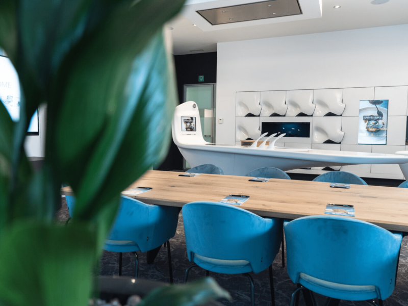 Meeting room with wooden table, blue velvet chairs and another higher white table