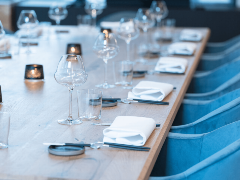 Meeting room with wooden table with cutlery, glasses and candles on the table