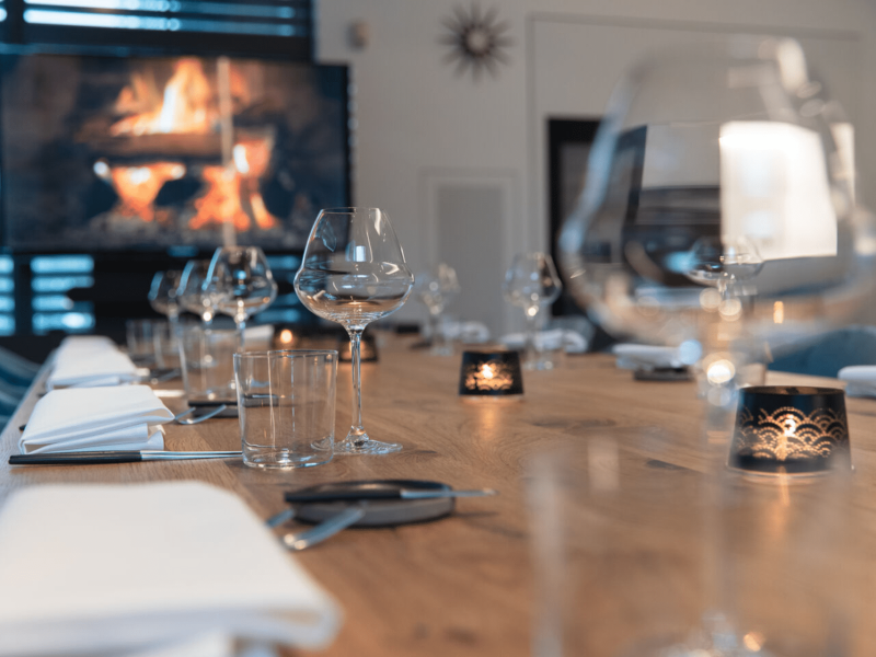 Meeting room with wooden table, fire place on the tv screen, cutlery, glasses and a candle on the table