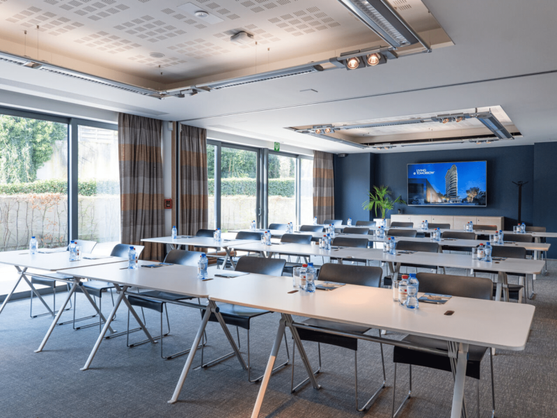 Meeting room at voco with bottles on table and tv screen on blue wall