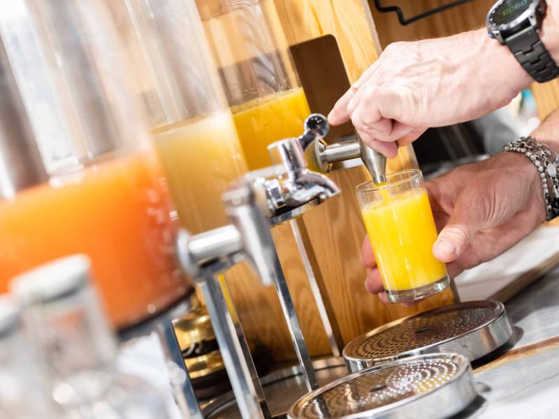 person pouring orange juice in glass